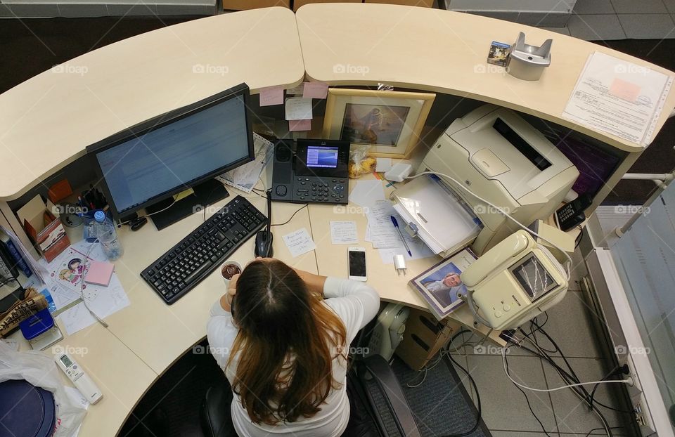 This is my colleague and her desk. She works at reception and her place is close to a staircase. I was walking by and took that picture. 