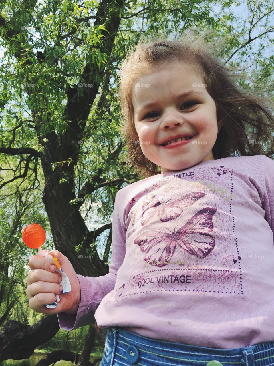 Funny girl laughing with lollipop 