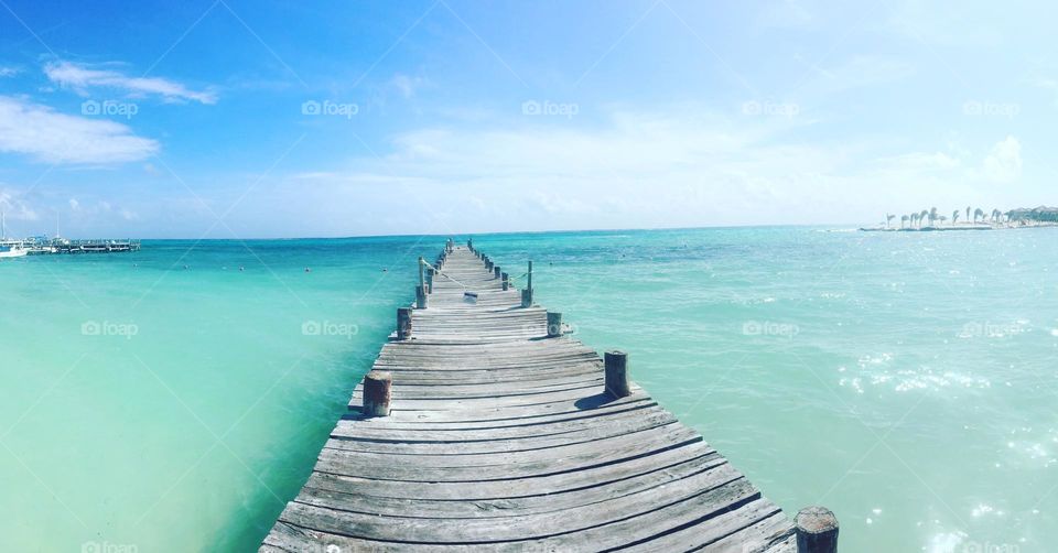 Pier extending out into beautiful clear blue ocean.