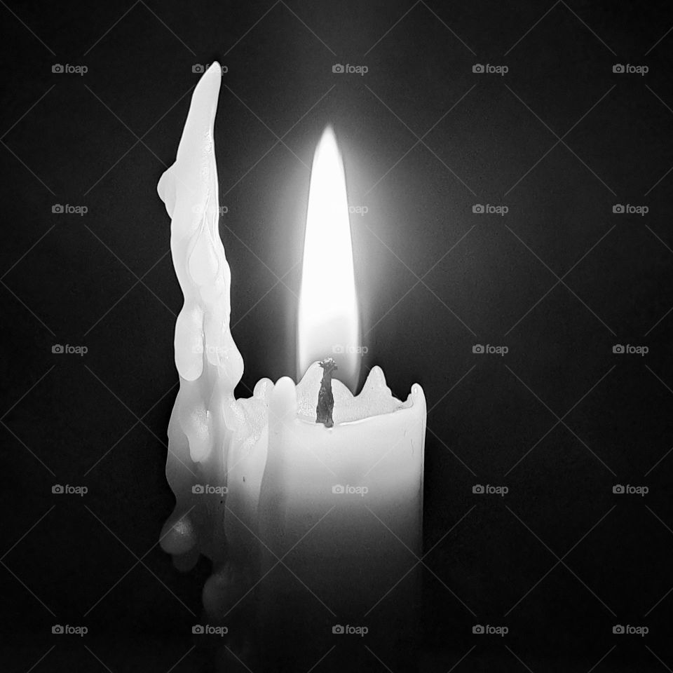 Black and white image of a burning candle flame and wax. light and shade