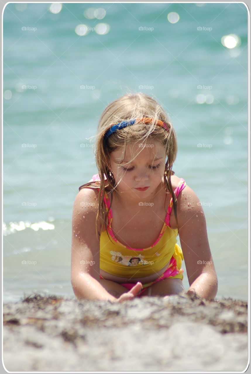 Little girl playing in the sand on the beach 
