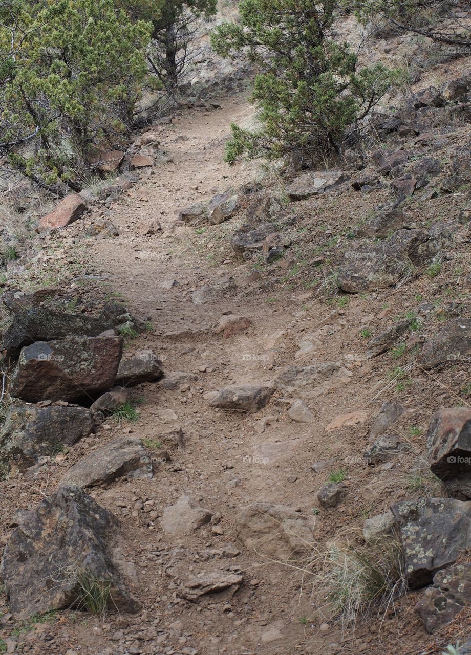 A rough and rugged hiking trail going uphill to Castle Rock in Crook County in Central Oregon on a spring day. 