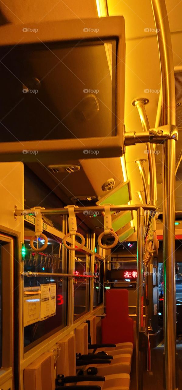 A retro-style bus with a warm yellow light interior.Safety equipment window breakers.bus seat.card reader.handrail ring