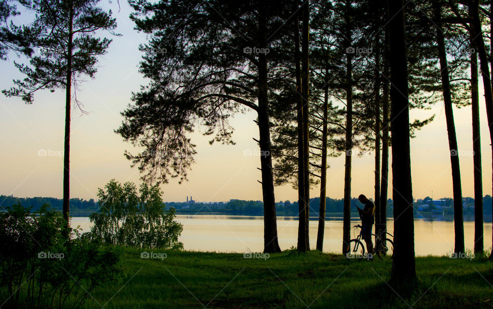 Person with bicycle in park at sunset
