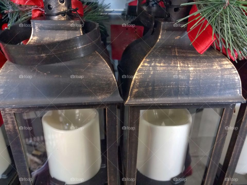 Two Christmas lanterns covered with ribbons and pine needles.