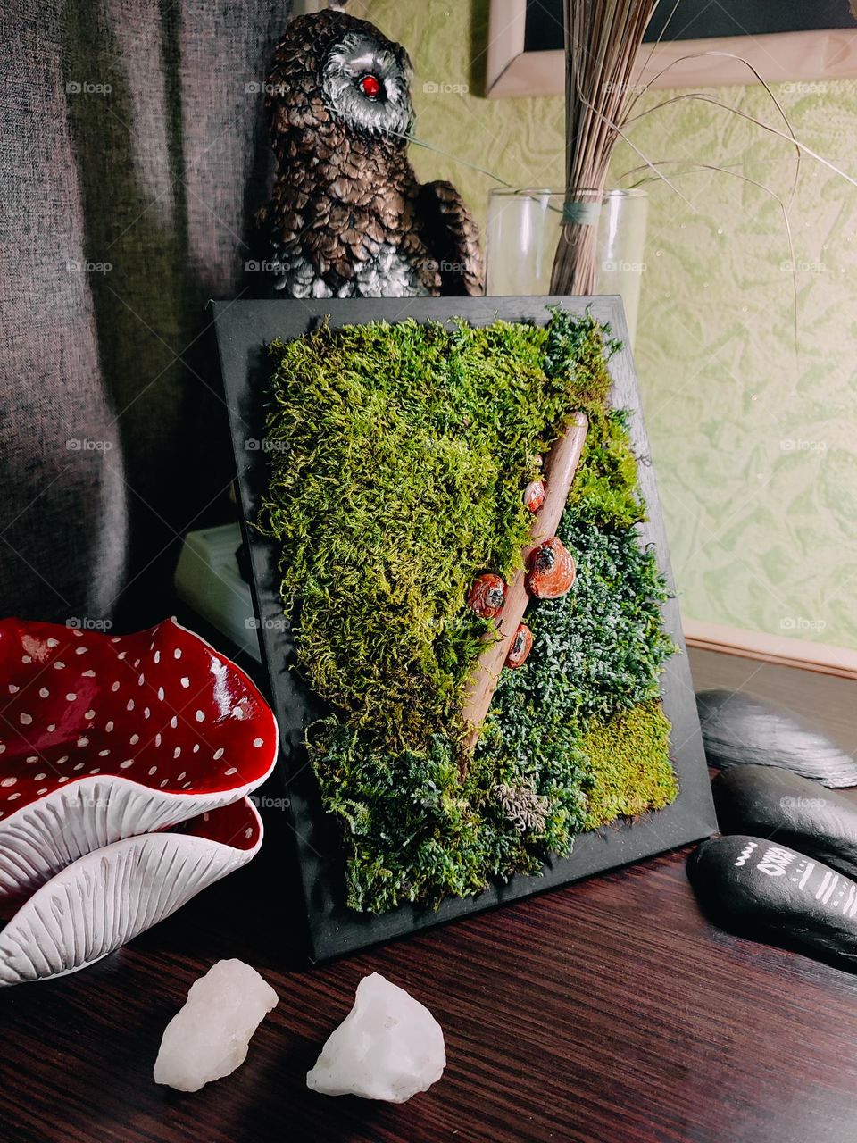 Moss picture art with mushroom on tree branch in black frame on the table. Home decor, art, craft