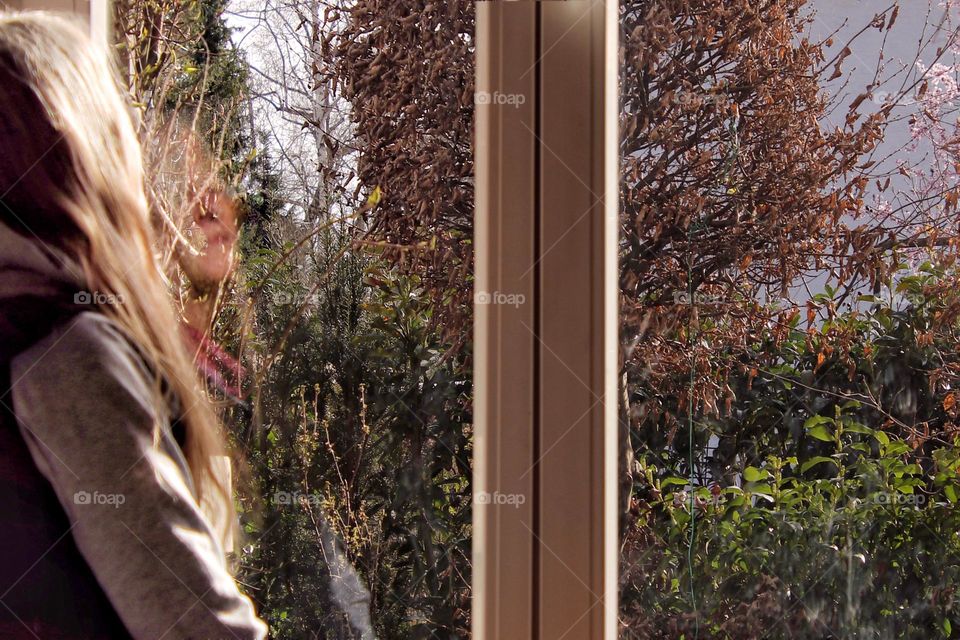 Woman with closed eye sitting in sun at window