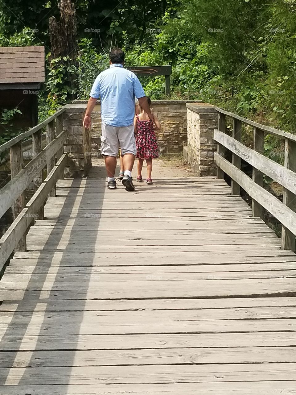 Father and daughter walking across a bridge