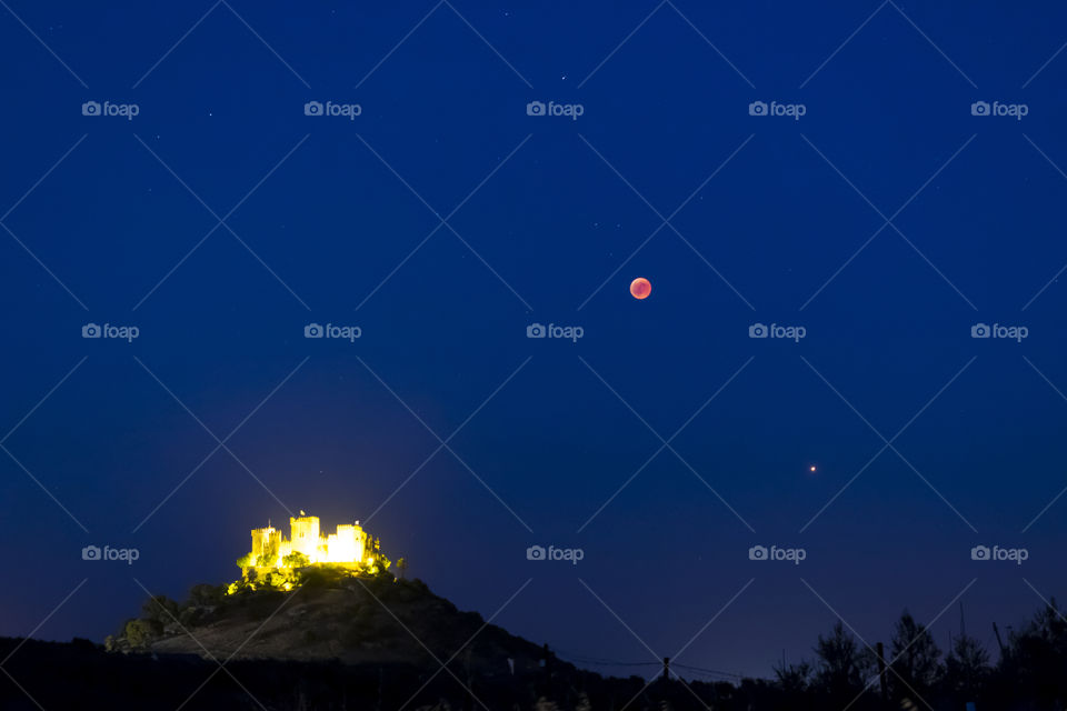 Moon total eclipse over a castle and mars