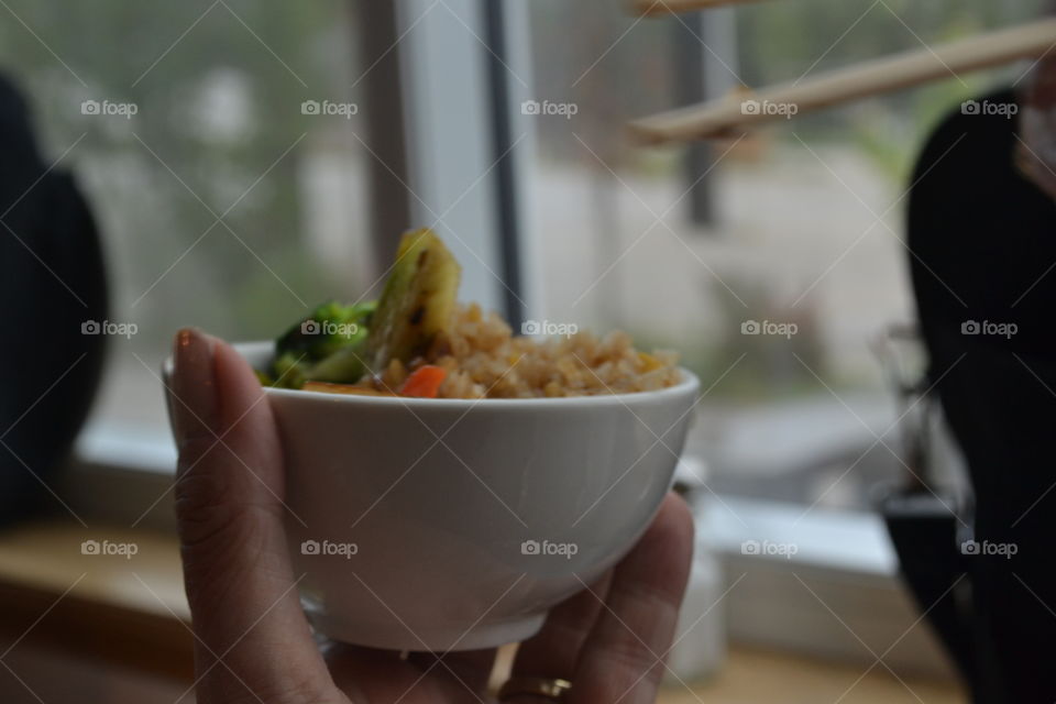 Woman eating Chinese food with chopsticks from bowl closeup 