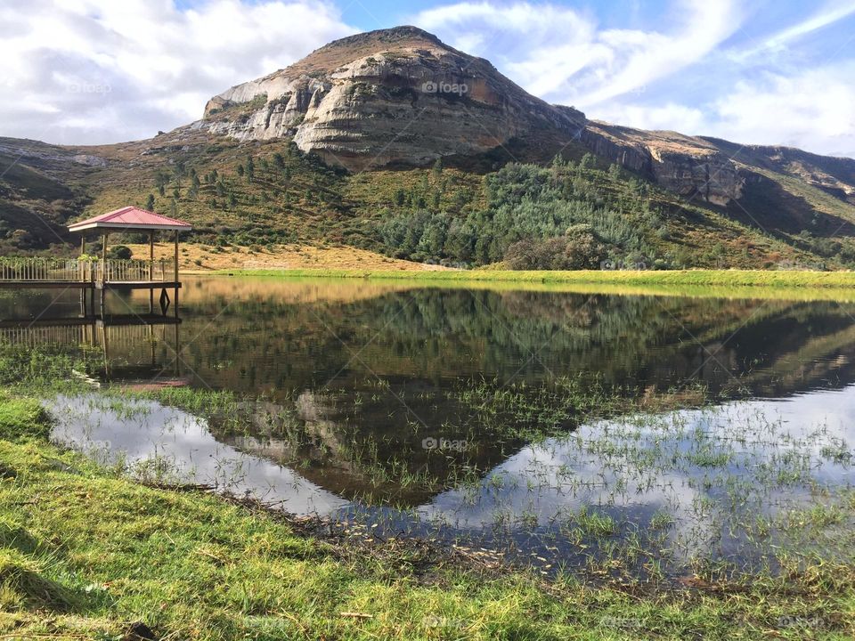 One of my best photos in nature- view of a mountain, clouds in the sky and little house structure in the small lake. Reflection in the water