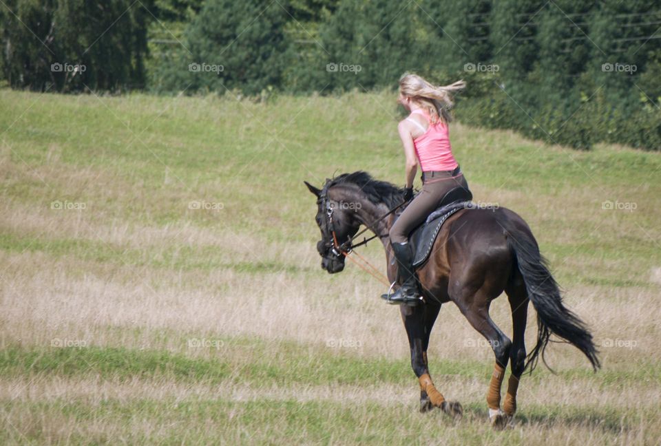 Girl jumps on the horses on the field