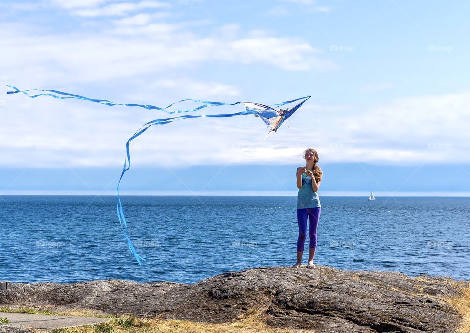 Girl flying a kite on the scenic ocean shore