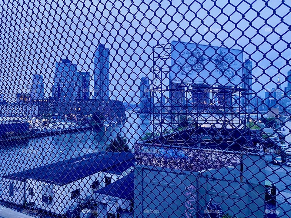 Through the wire mesh on top of the “Pulaski Bridge” sealing off the pedestrian lane from the free fall that could happen were it otherwise we see “Greenpoint”, Bklyn, “Newtown Creek”, LIC and “Manhattan”. 2023. Hypnotic Productions