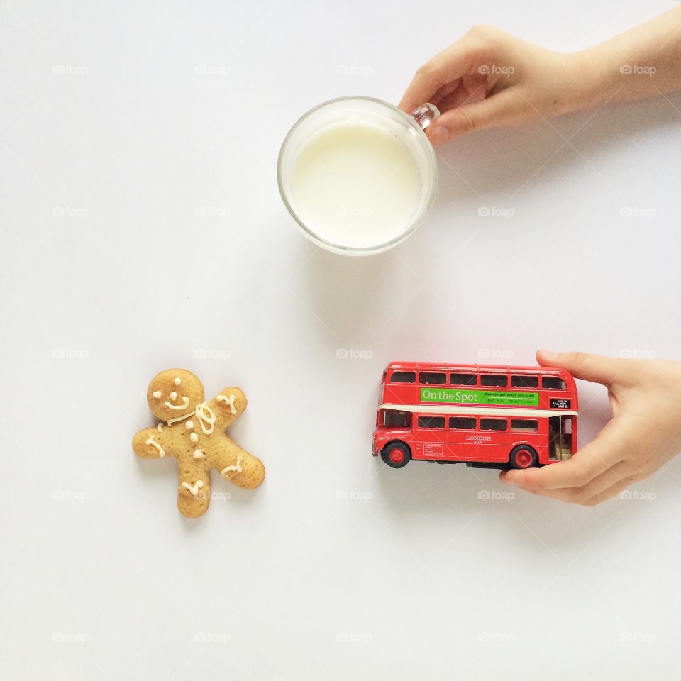 Person holding cup of milk and toy bus