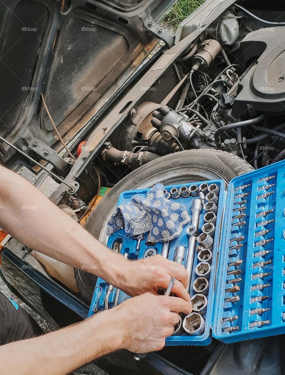 A mechanic checks with a toolbox before repairing an old personal car