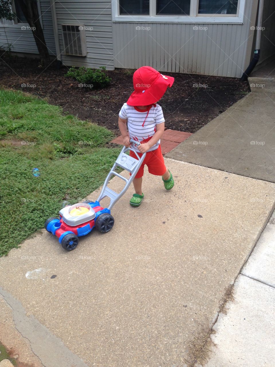 Toddler boy pretending to mow the lawn.