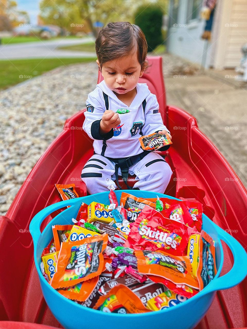 Little girl with Halloween candy, baby girl inspects Halloween treats, riding in wagons with treats, Trick or Treating with kids, fun on trick or treat night, baby girl dressed up as an astronaut