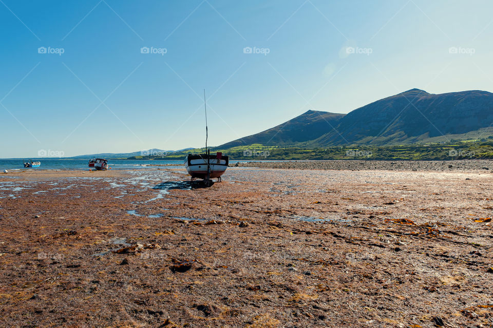 Fishing boat on beach during low tide.