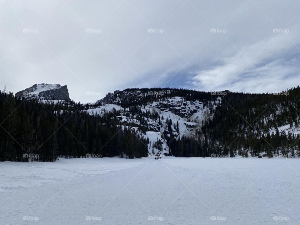 Walking over a frozen, snow covered lake towards the mountains. 