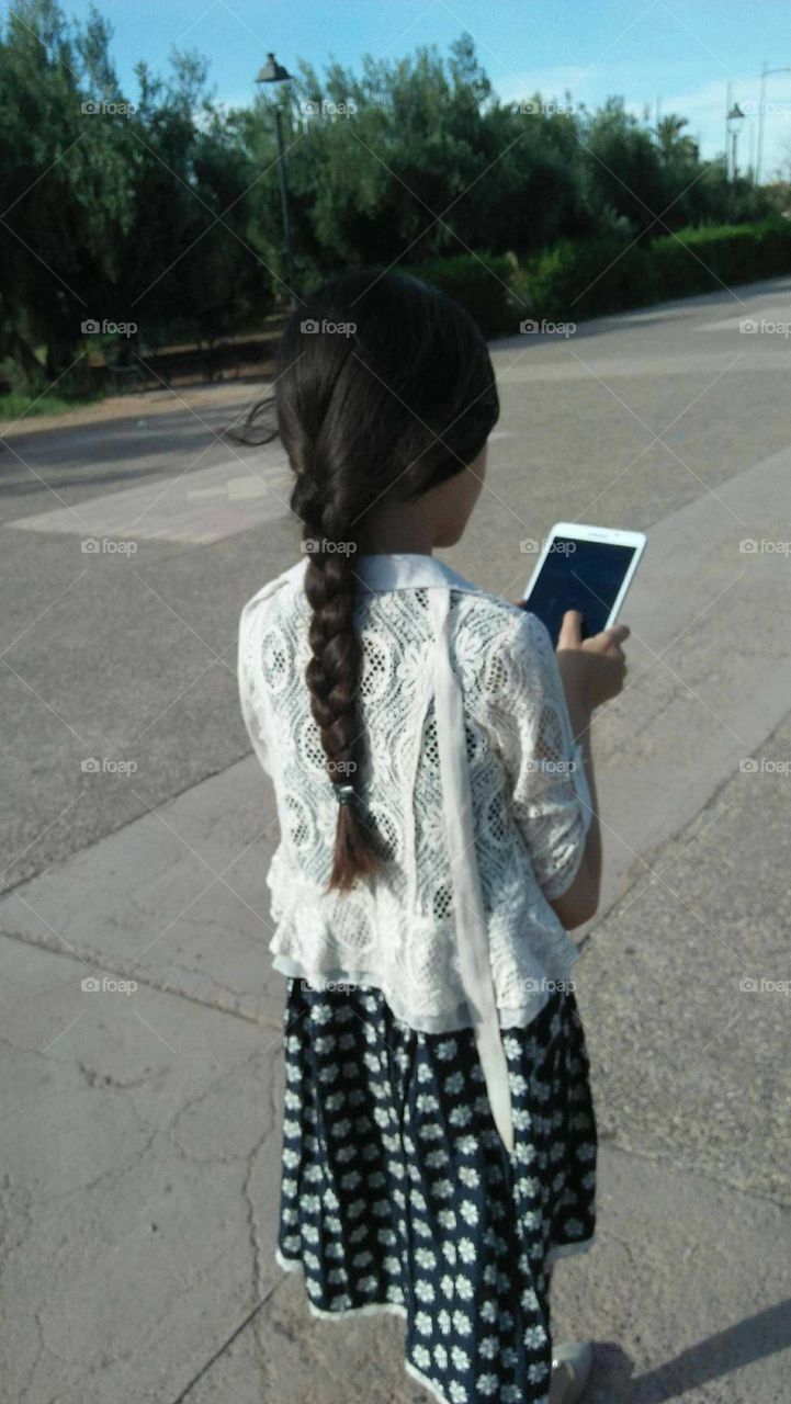 A young girl holds its mobile phone