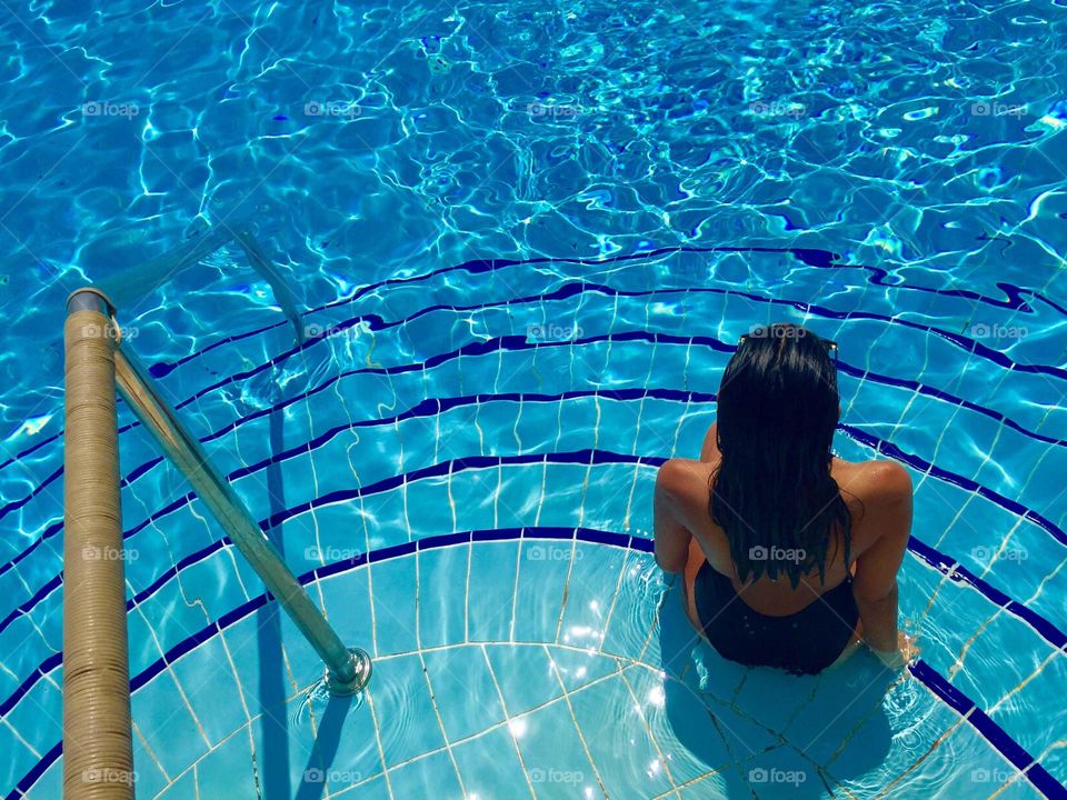 Rear view of women sitting in pool