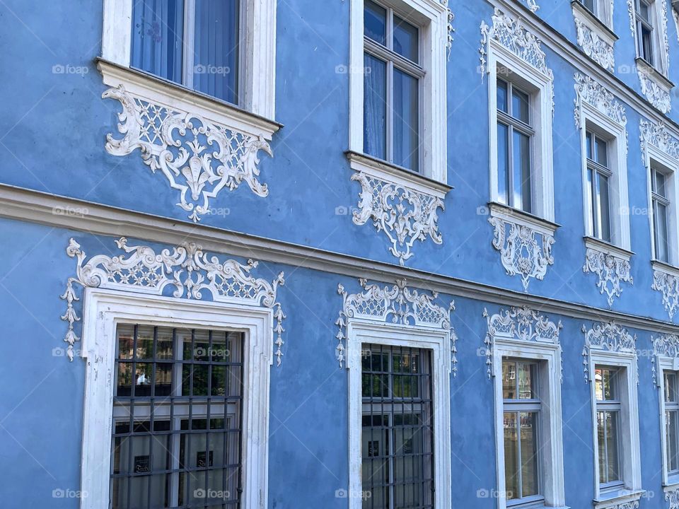 Blue house with white baroque painting around the windows 