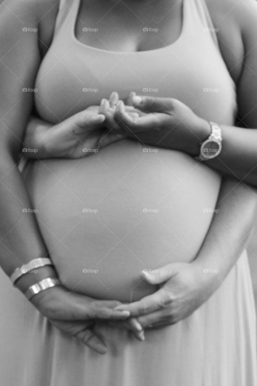 Couple holding hands around baby to be