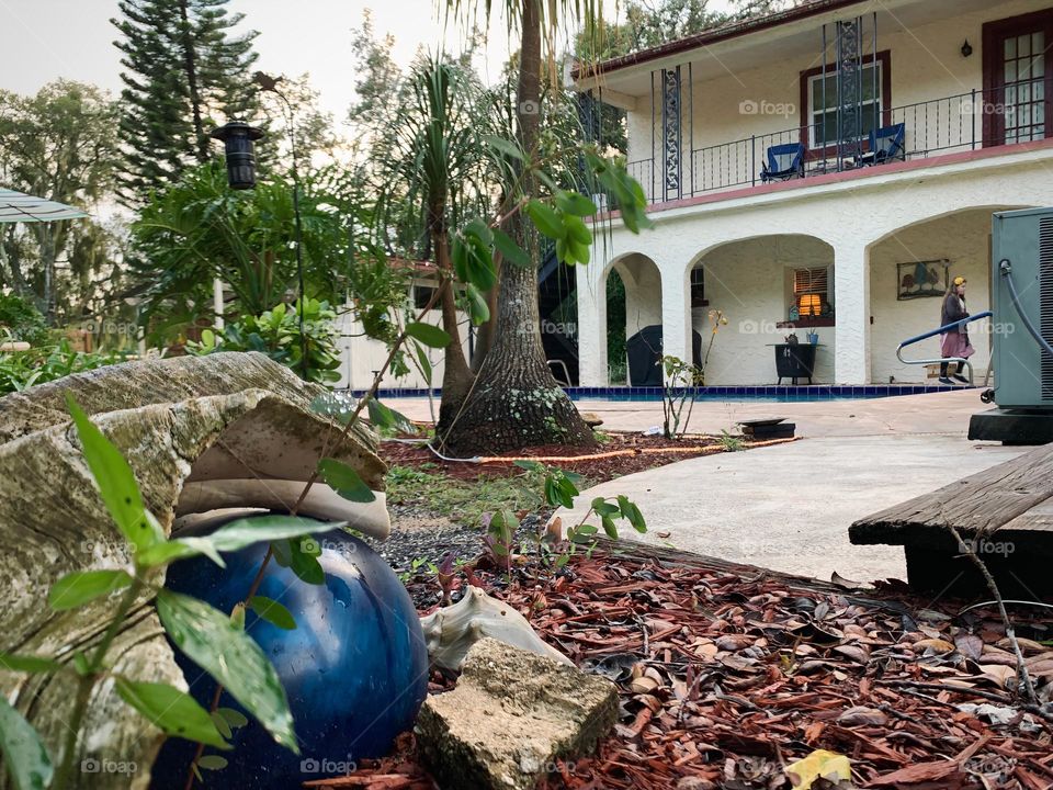 Gated white and red spanish old style architecture residential large house built in the early 1900s. Charming style and beautiful landscaping with pool and great setting in a tropical environment with arched openings in patio area with large shell.