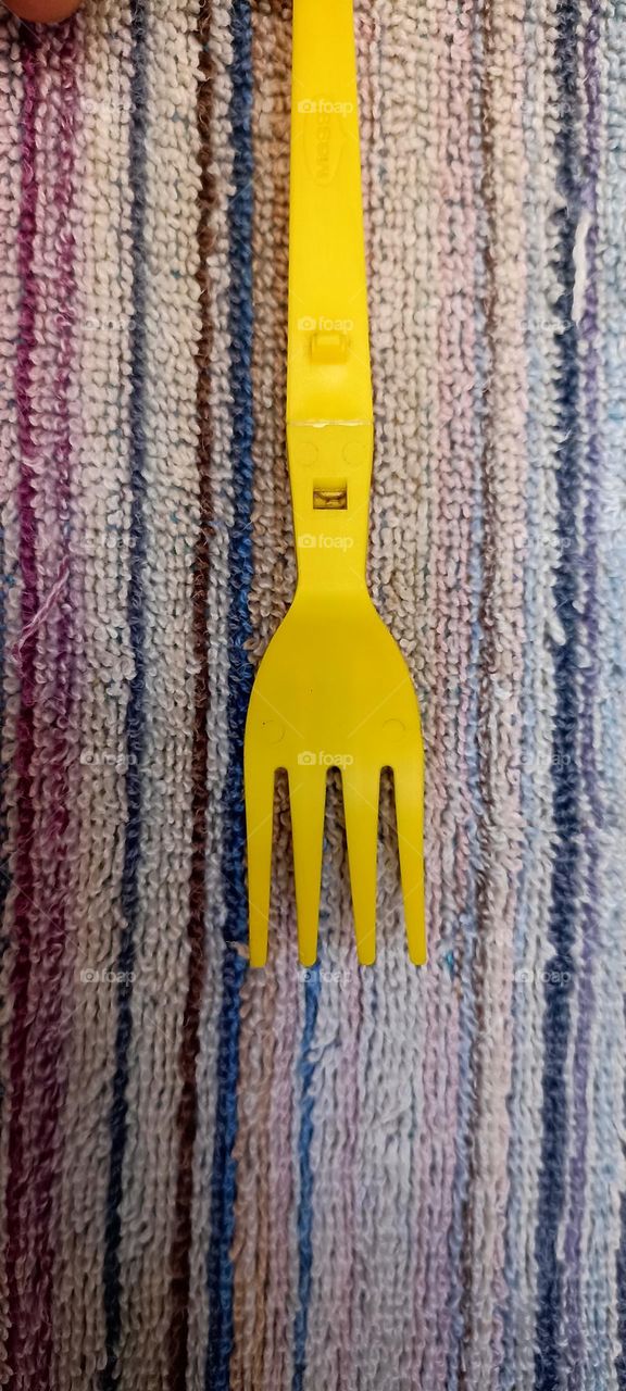 yellow fork on colored stripes towel  as parallel to the lines.