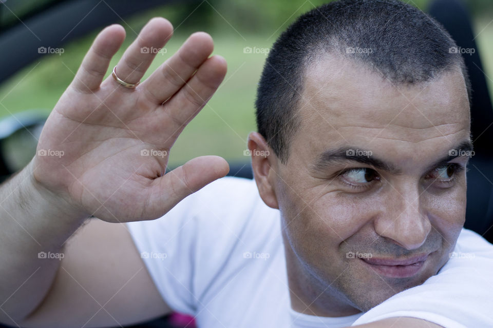 man waving from car. man waving from car while looking back and smiling