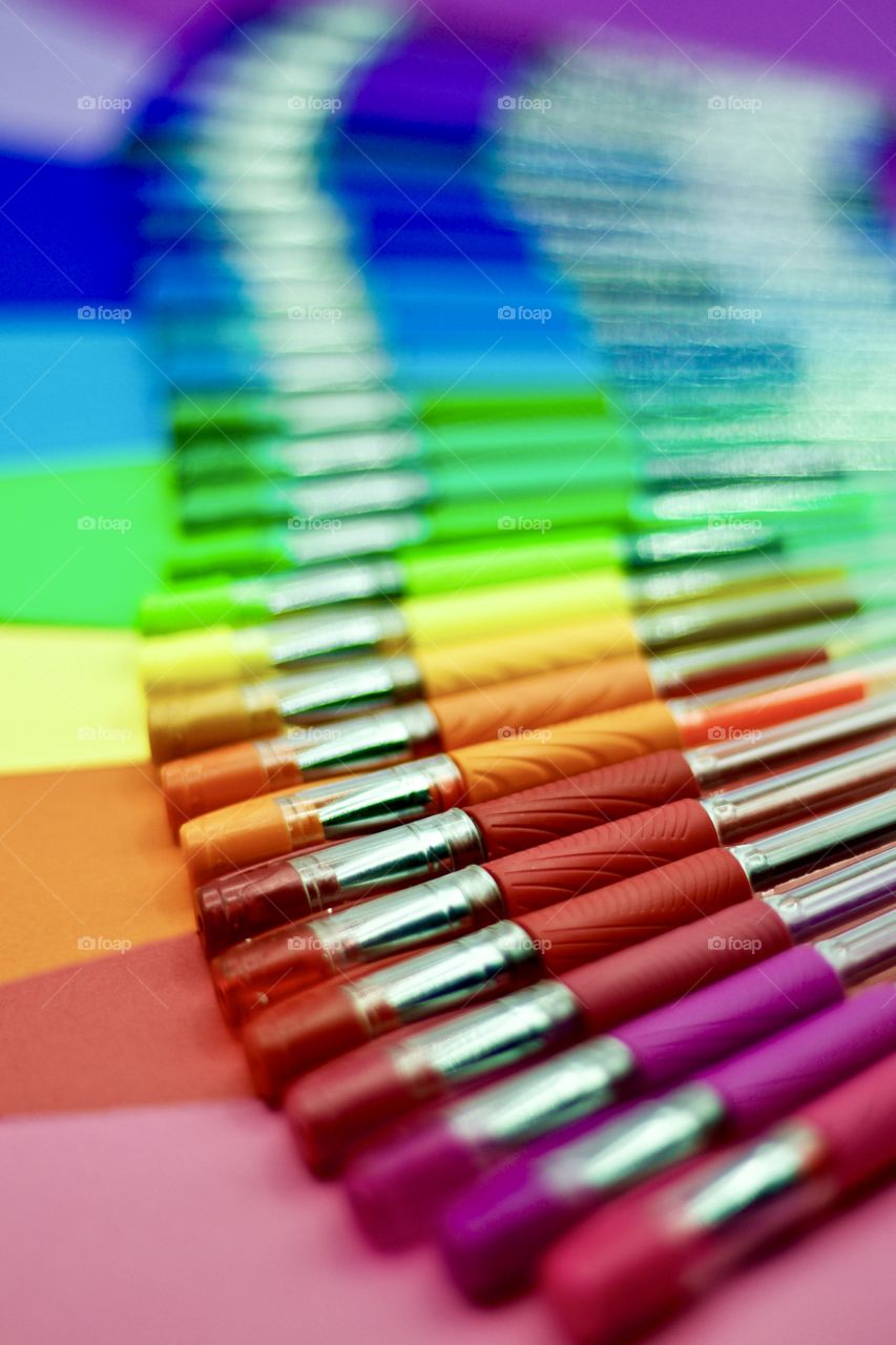 Color Love - low-angle, abstract closeup of gel pens in an array of vivid colors, arranged on matching-colored paper