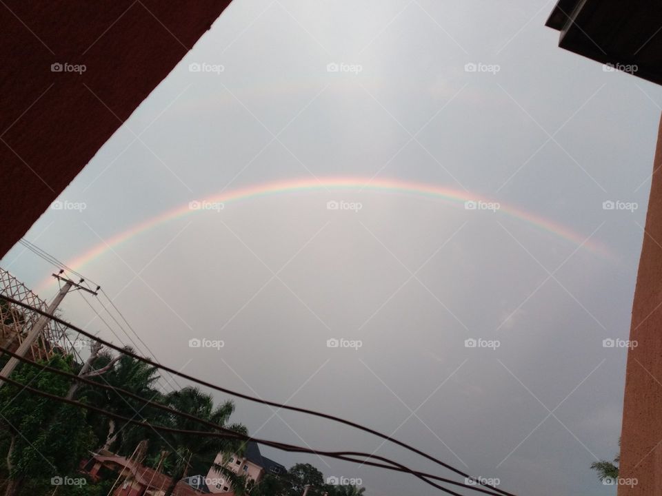 A Beautiful rainbow in the sky, but at the same time looks like a drawing in a sheet of paper.