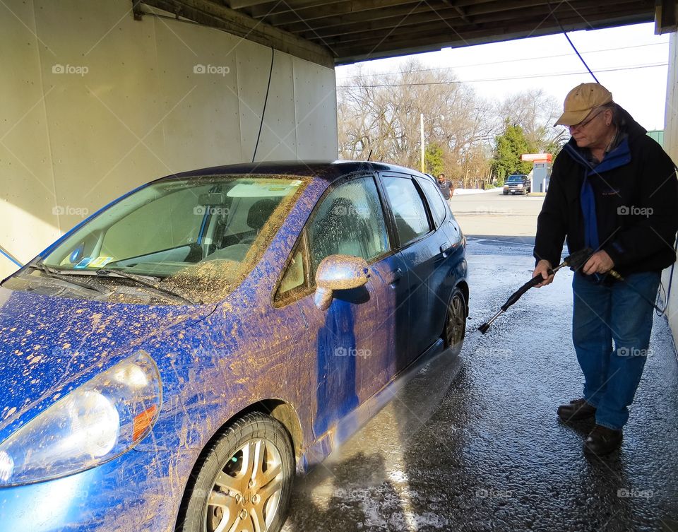 Man washing car using water hose