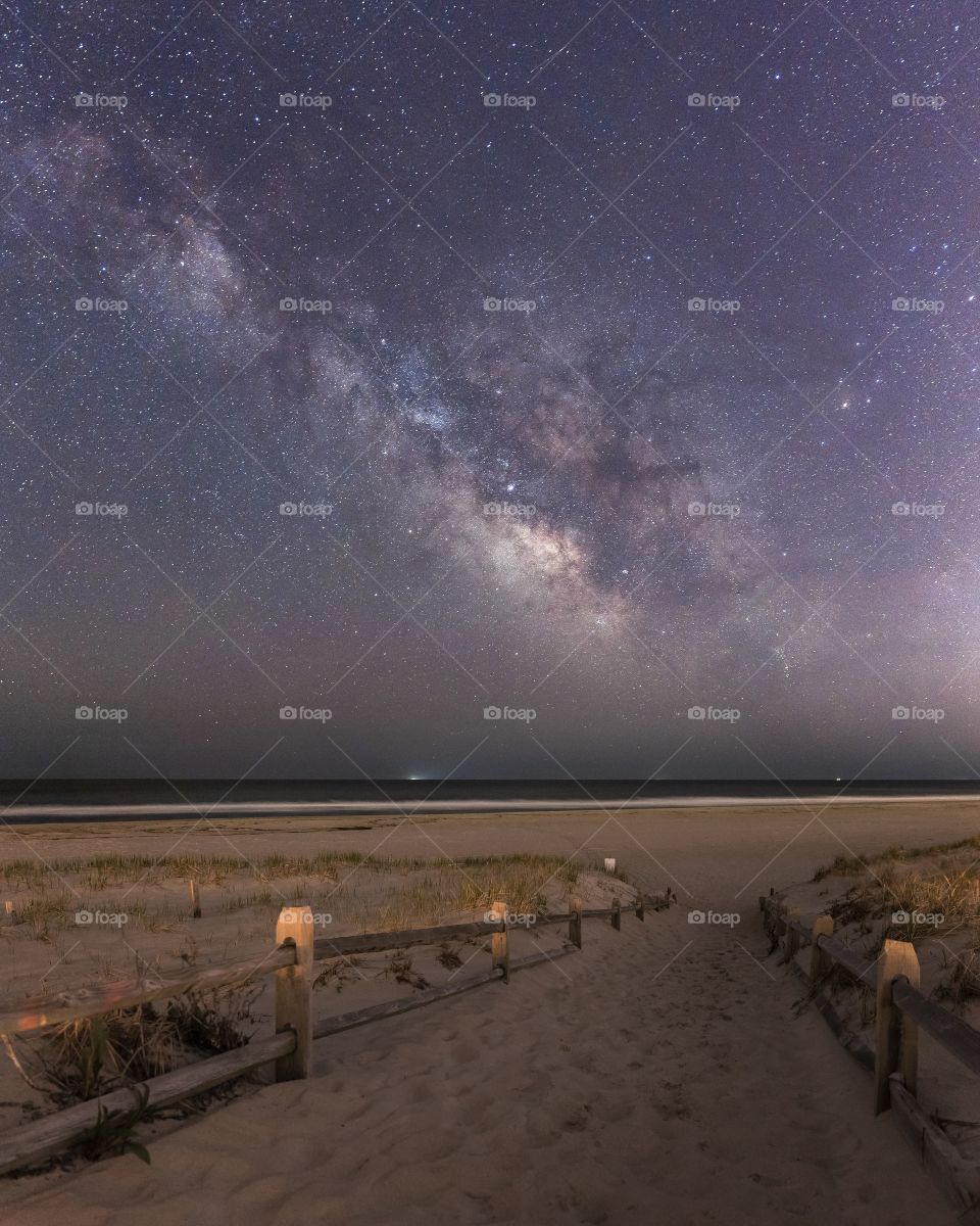 Sandy beach path leading straight into the Milky Way rising over the ocean