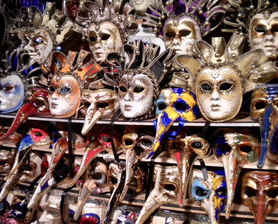 Hand made and painted typical Venetian carnival masks on sale displayed on shelves in a store 