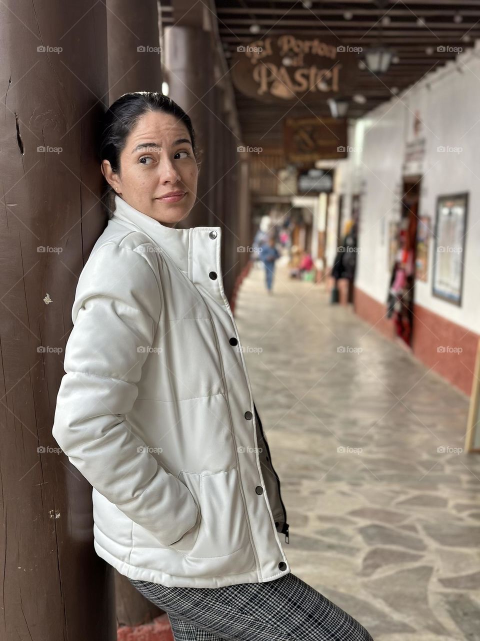 Portrait of woman leaning on a wooden post on the downtown street.