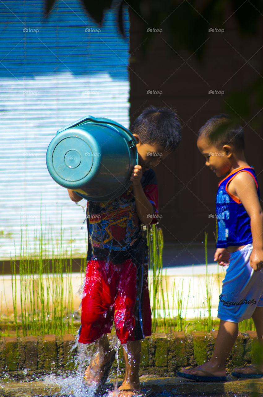 Boy splashing himself with bucket of water