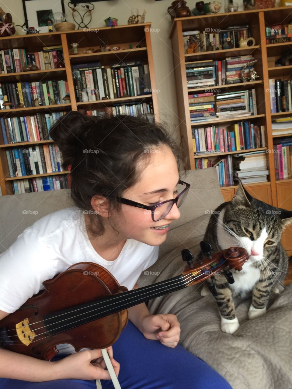 Teenager girl holding guitar sitting on sofa with a cat