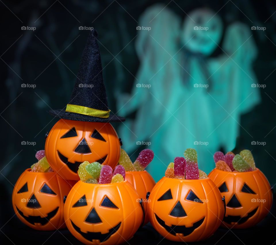 Plastic pumpkin in wide brimmed hat with others full of jelly sweets, while an actual ghost, glowing with ectoplasm, hoovers menacingly in the background.
