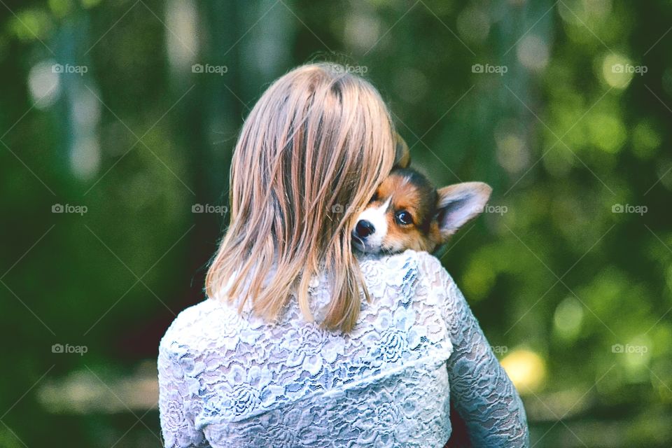 Rear view of a woman carrying cute puppy