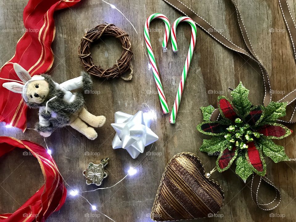 Rustic Christmas flat lay with brown heart, red ribbon, white lights, and a white bow on a wooden background 