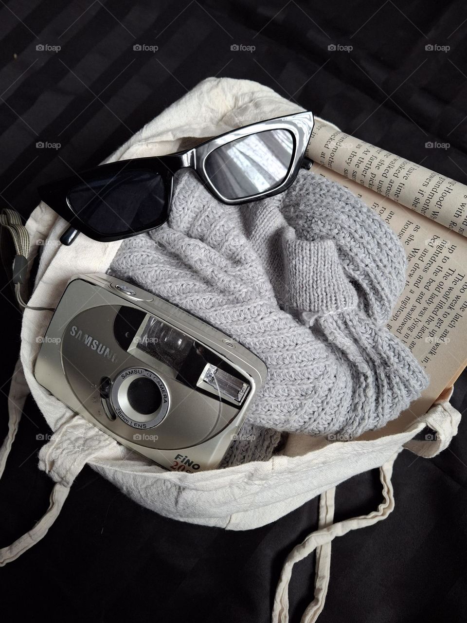 film camera and glasses with a knitted sweater lie in an eco bag