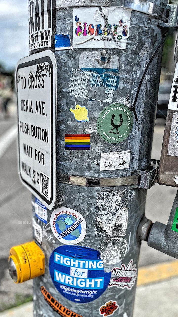 Pole at traffic light with Pride flag sticker on it, Pride colors in everyday life, colors of Pride in the city, colorful stickers on traffic signal poles, crossing the street 