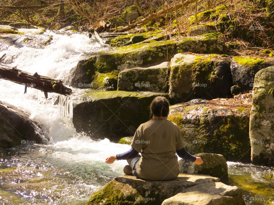 Rear view of a woman meditating on rock