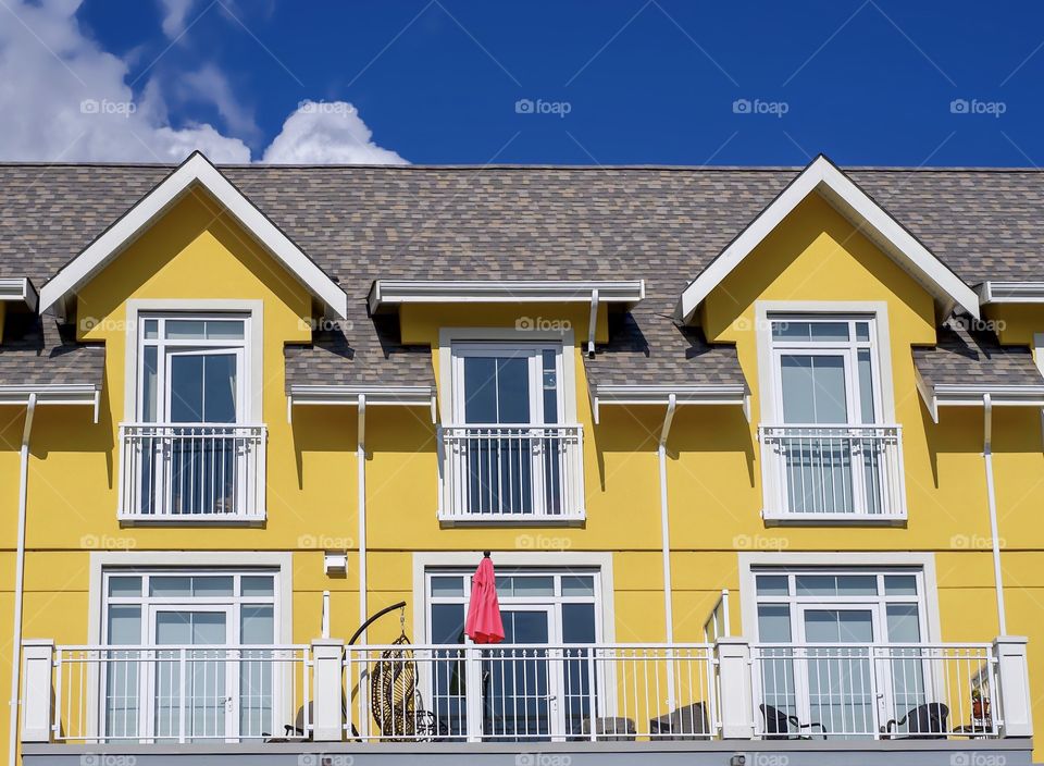 Bright yellow building with a red sun umbrella under a bright blue sky - colorful contrast