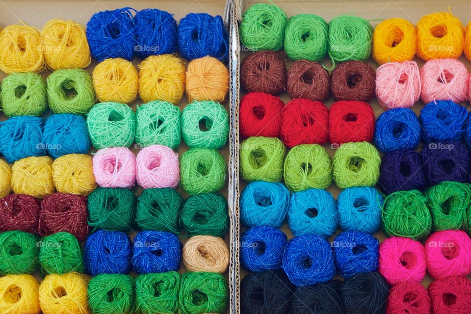 Many multicolored balls of yarn displayed outside in upright open boxes for sale on the street in San Miguel de Allende, Mexico.