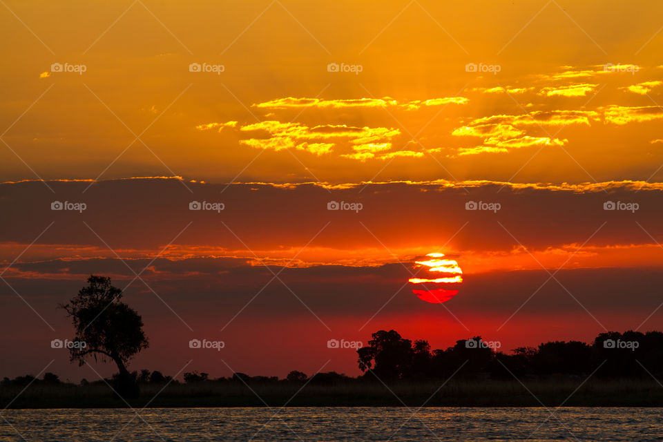 Red yellow and orange Sunset with sun in the clouds. Sunset over Chobe river in Botswana Africa. Dramatic and colorful sunset with amazing colors.