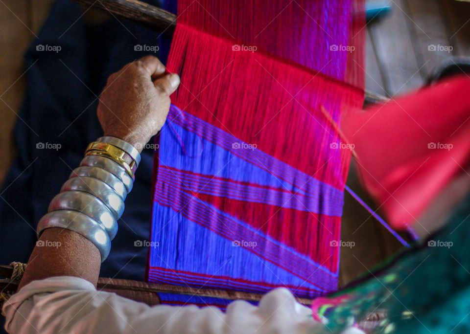 Rear view of woman weaving thread at industry