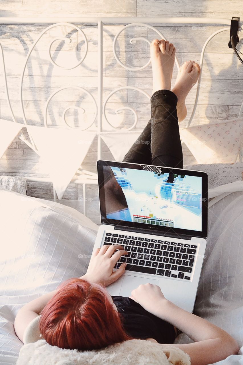 Woman lying on bed working on laptop